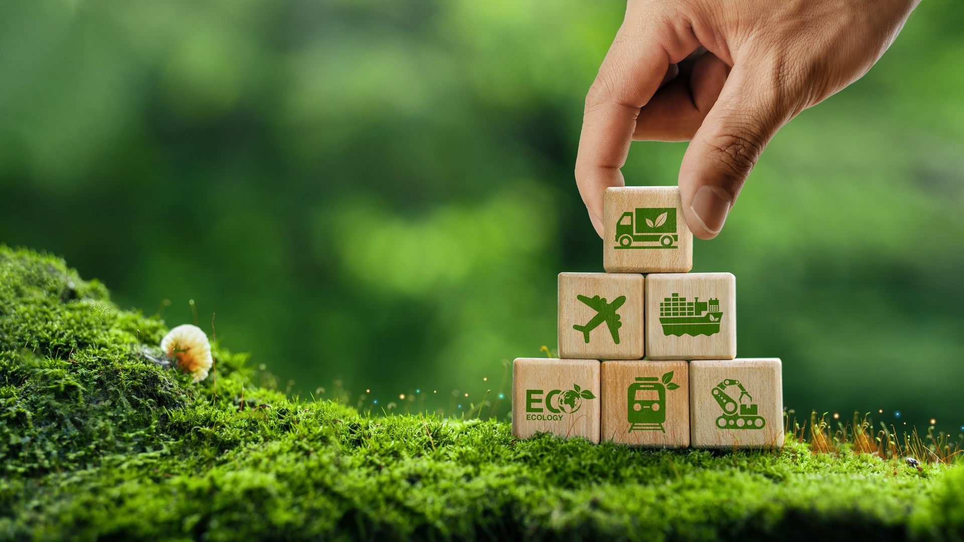 Green logistics or sustainable transportation concept. Air, sea and land transport. Eco-friendly transport. Hand holding wooden block with green logistics icon on green background.